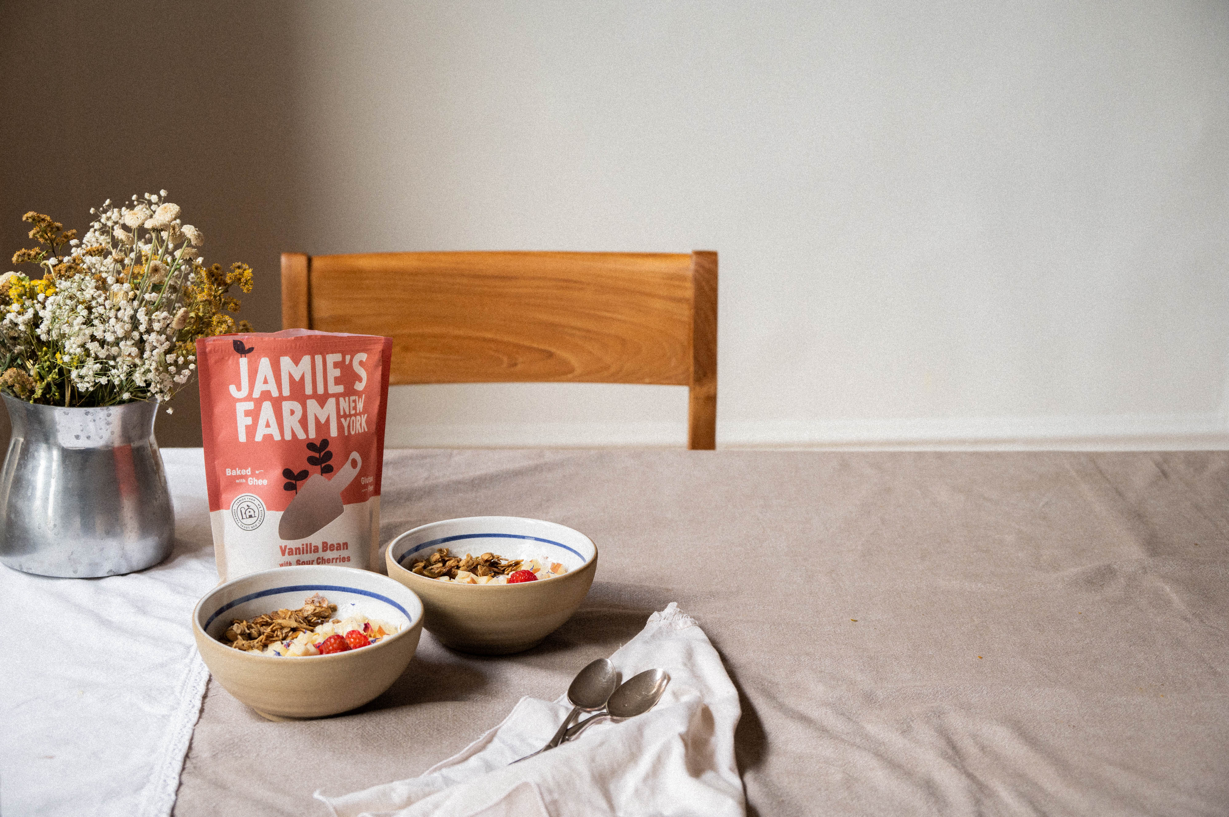 Breakfast scene with cereal granola and bowls on a table.